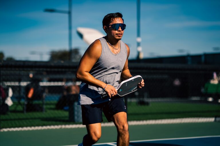 Player in sunglasses moving into a ready position with his paddle held in front